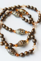Elegant handcrafted necklace made of brown and bronze beads. Sophisticated bijoux close up on white background. Women's fashion, female accessory, bijouterie, costume jewelry.