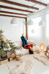 a woman in the Christmas decorated rom with a spruce tree ms Santa