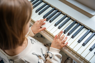 Home lesson on music for the girl on white piano synthesizer. Concept of early development:...