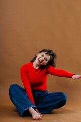 A fashionable young woman in a bold red top and wide-leg denim jeans strikes a dynamic and artistic...