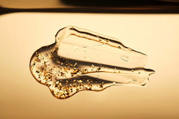 A delicious drop of 24k gold serum on a gold background.