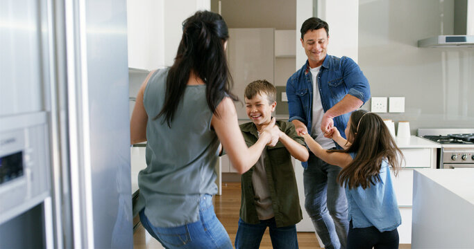 Happy, parents and children with dancing in kitchen for celebration, bonding or learning steps. Energy, woman and man with kids in home for moving together with weekend entertainment, support or love - Powered by Adobe