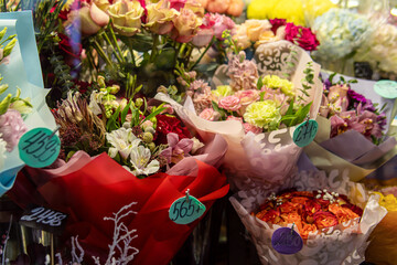 Decorated bouquets of various flowers with price tags in the flower shop. Soft focus