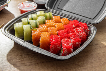 Sushi set in a disposable box. Asian food delivery. Sushi with caviar and salmon closeup