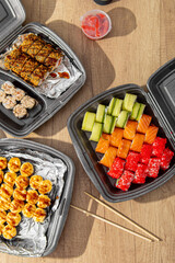 Several boxes of sushi sets on wooden table. Vertical. Asian food delivery at home