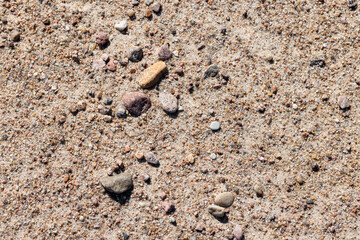 Small stones are in coastal sand on the shore of the Baltic Sea