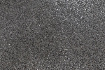 Dark gray wet shore sand, natural background texture
