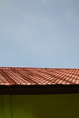 A textured terracotta tiled roof against a bright blue sky showcases architectural detail