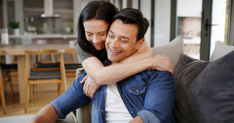 Fototapeta premium Happy couple, hug and love for man in home, romantic commitment and loyalty in support on couch. People, smile and embrace trust in relationship on sofa of lounge, care and security in marriage