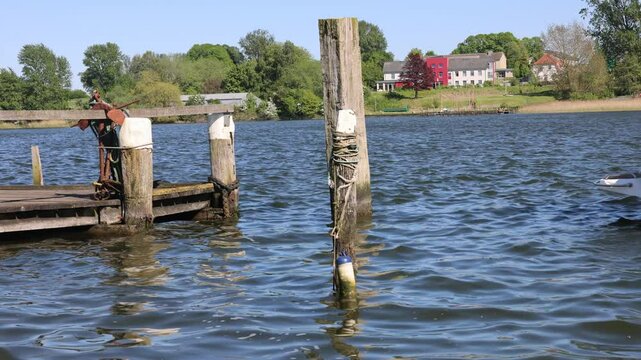 Tranquil river scene with wooden pier and distant houses on sunny day in Arnis a tiny City in Germany