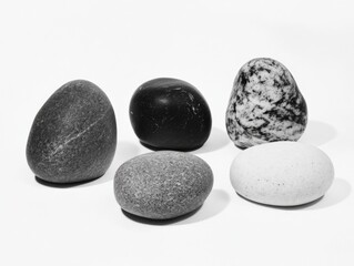 five smooth rocks of varying sizes, shapes, and colors on a white background
