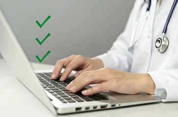 Fototapeta premium A healthcare professional typing on a laptop, indicating task completion with green checkmarks.