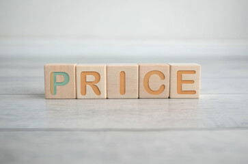 The image features wooden blocks arranged to spell the word "PRICE" on a smooth surface, emphasizing the concept of value and cost.