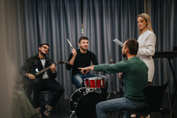 A group of musicians practicing together in a studio environment, preparing for a performance or...