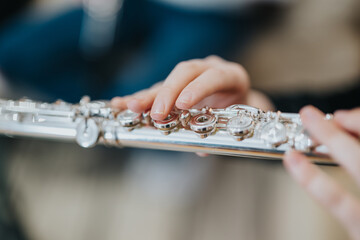 A detailed image showing hands playing on a silver flute, highlighting the intricate keys and...