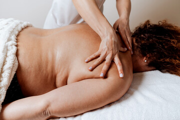 Fototapeta premium Obese middle-aged woman receives a special body massage intended for weight reduction and correction of bad posture. Modern weight loss physical therapy and beauty spa concept.
