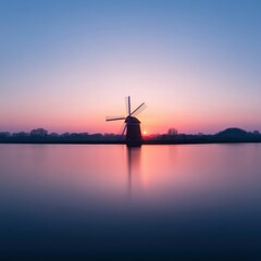 silhouette of a windmill at sunset reflected in calm water