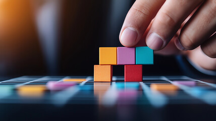 Naklejka premium Close up of hand placing colorful wooden cubes on grid, showcasing creativity and focus. vibrant colors and arrangement highlight playful yet strategic approach to building