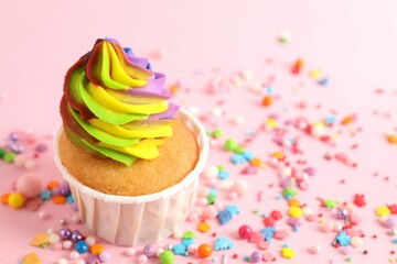 One delicious cupcake with colorful cream and sprinkles on pink background, closeup. Space for text