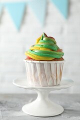 Delicious cupcake with colorful cream on grey textured table against blurred background, closeup