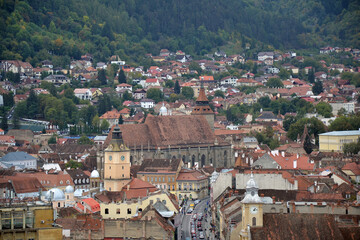 This panoramic view of Brașov highlights the Council Square, surrounded by historic buildings with...