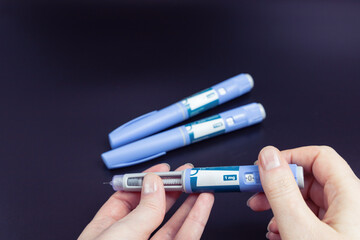  Insulin injection pen on a dark background for diabetics and weight loss.