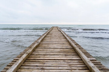 Fototapeta premium Wooden pier leading to the Adriatic Sea on a cloudy autumn beach in Italy