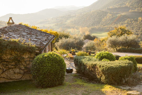A serene Tuscan landscape featuring rustic houses, lush greenery, and rolling hills under soft sunlight. A perfect depiction of rural charm and natural beauty