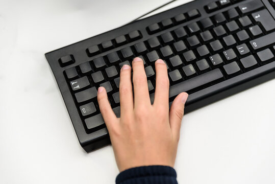 Student typing on black keyboard learning programming language