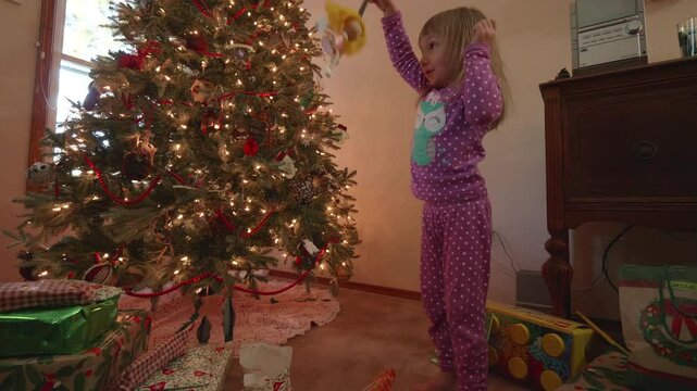 Little Girl Playing with a Spring Yoyo Toy Under the Christmas Tree