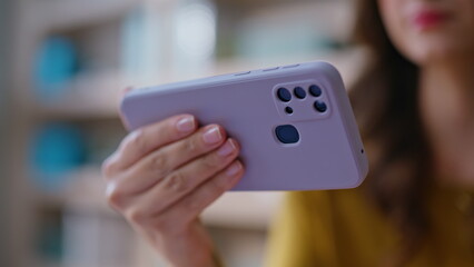 Hand holding horizontal cellphone in apartment closeup. Unrecognizable woman