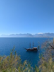 Enjoy the serene coastal scenery with a traditional ship gliding over beautiful blue waters