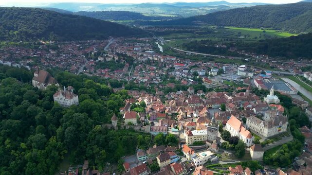 Aerial perspective of historic centre of Sighisoara, Romania. It is a popular tourist destination for its well-preserved old town, which is listed by UNESCO as a World Heritage Site. Camera tilt down.