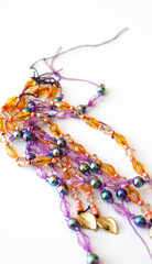 Strands of colorful acrylic beads for Brazilian Carnival decoration and costumes. Purple and orange color beaded cords in detail. Strings abstract vertical background.