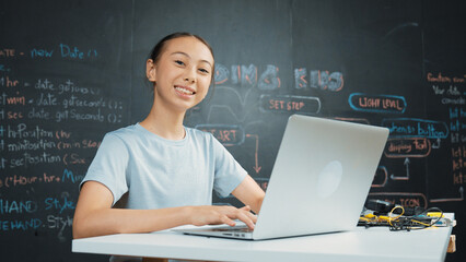 Smart girl programing system by using laptop at blackboard. Highschool student writing engineering...