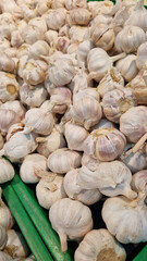Garlic close up in supermarket. Lots of garlic in plastic green box on market stall. Garlic in green plastic box at farmers market. Garlic for sale in store. Display of fresh produce for sale