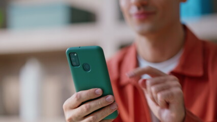 Joyful man browsing mobile phone app sitting apartment closeup. Smiling manager