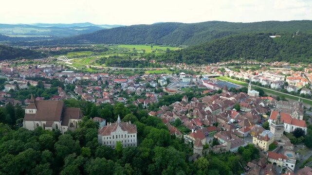 Sighisoara, Romania, Drone circling above historic city center. Church in top of the hill. Sighisoara Fortress. Panoramic view of all region. Tarnava Mare River in background. Travel destination.