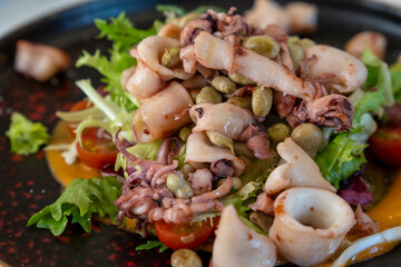 Salad with little squids on black plate for statrte in Spain