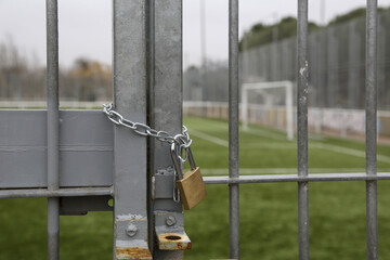 Padlock and chain closing the gate of a soccer field. Concept: freedom, prohibition