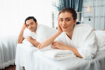 Fototapeta premium Caucasian couple customer enjoying relaxing anti-stress spa massage and pampering with beauty skin recreation leisure in day light ambient salon spa at luxury resort or hotel. Quiescent