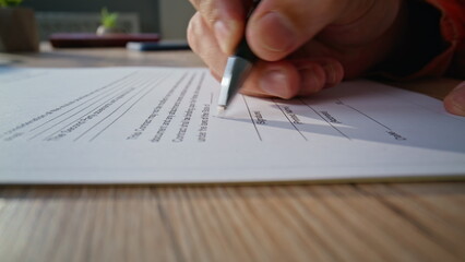 Closeup hand signing document in professional office. Unrecognizable businessman