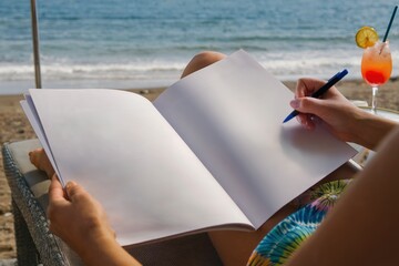 Person Writing in a Blank Notebook While Relaxing on the Beach