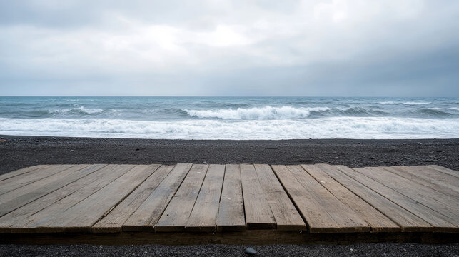 Wide-angle minimalist photo of an isolated wooden platform on a wide black sand beach, with crashing waves and a moody overcast sky in the background, creating a serene and contemplative atmosphere