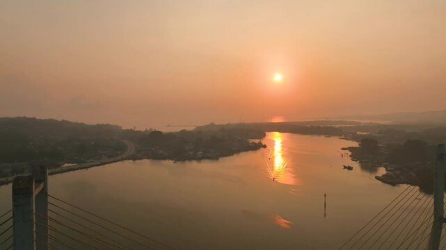 4k aerial footage of the sunset on the Kendari Bay Bridge which has become a tourist icon in Southeast Sulawesi, Indonesia. Golden yellow twilight aerial panorama of the iconic suspension bridge