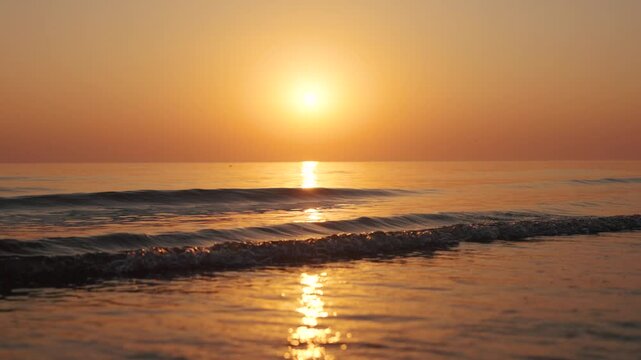 4K Slow motion shot of a beautiful sunset at Mandvi Beach in Kutch, Gujarat, India. Sea waves and entire sea becomes golden in colour during the sunset. Orange colored sea. Natural sea background.