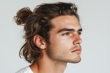 Fototapeta premium Profile of a fashionable young man with long brown hair tied in a bun, showcasing a trendy hairstyle