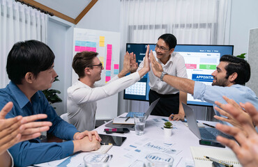 Happy office worker and project manager celebrate in meeting room after successfully achieving...