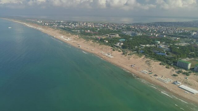Beautiful beach with a city in the background. The ocean is calm and the sky is clear. The Black Sea coast in Anapa at the height of the summer season.