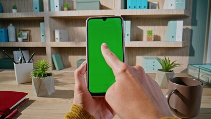 Businesswoman tapping greenscreen cellphone at workspace closeup zoom in.